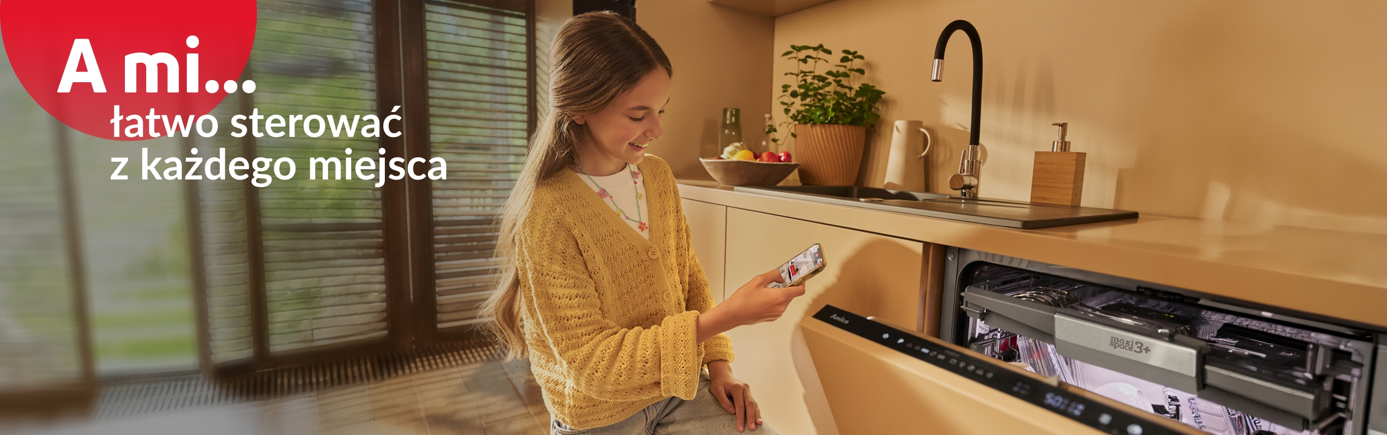 Dziewczyna przy otwartej zmywarce, z telefonem w ręce, sprawdza aplikacje