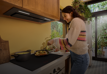 Kobieta stoi przy okapie w żółtej kuchni