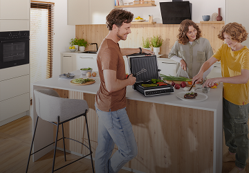 Tata z dziećmi szykuje jedzenie na grillu elektrycznym