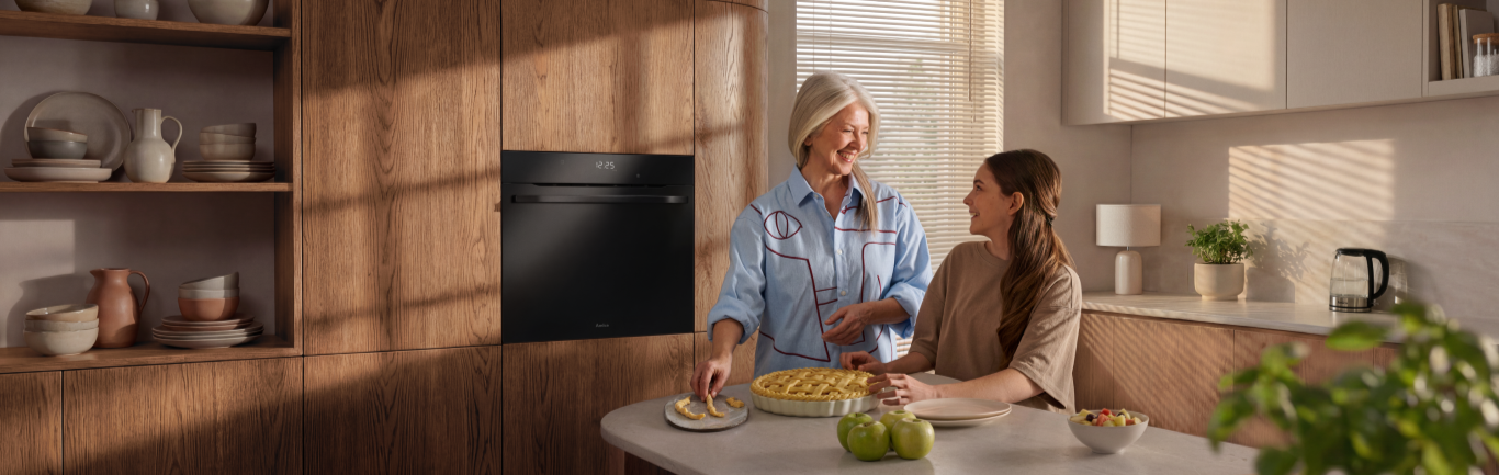 Babcia z wnuczką gotują tartę w kuchni, w tle piekarnik