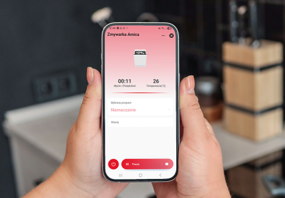 telefon trzymany w dłoniach, na ekranie wyświetla się aplikacja