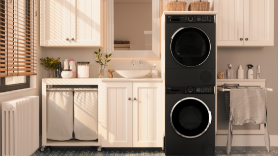 Biała kuchnia z czarną pralką i suszarką. Sprzety ustawione sa jeden na drugim.