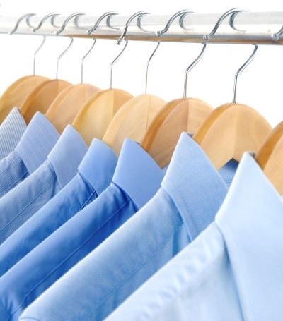 koszule w r&oacute;żnych odcieniach koloru niebieskiego wiszą na wieszaku