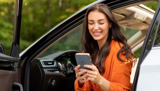 kobieta siedzi w samochodzie, sprawdza telefon 