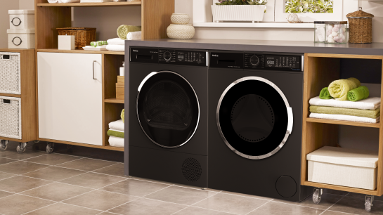 Biała kuchnia z czarną pralką i suszarką. Sprzęty ustawione sa jeden obok drugiego.