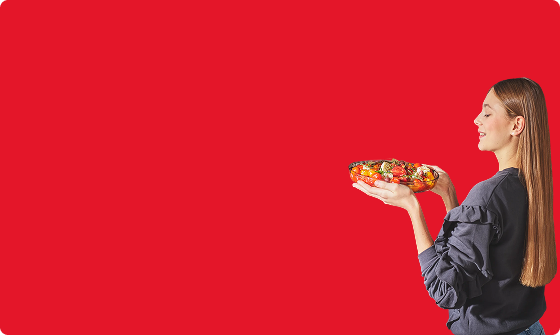 dziewczyna z potrawą w misce, kt&oacute;rą trzyma w dłoniach na czerwonym tle