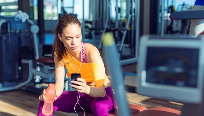 dziewczyna na siłowni z telefonem w ręce