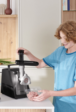 chłopiec mieli mięso w maszynce do mielenia