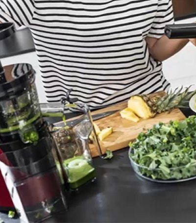 kobieta wyciska sok przy użyciu popychacz od wyciskarki