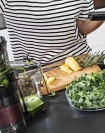 kobieta wyciska sok przy użyciu popychacz od wyciskarki