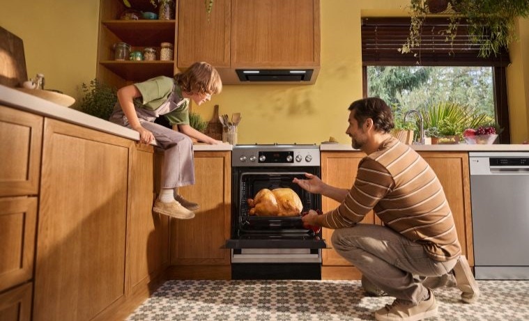 tata z synem pieką indyka w kuchni wolnostojącej
