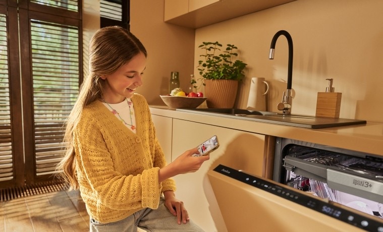 dziewczyna steruje zmywarką z aplikacji Amica Smart