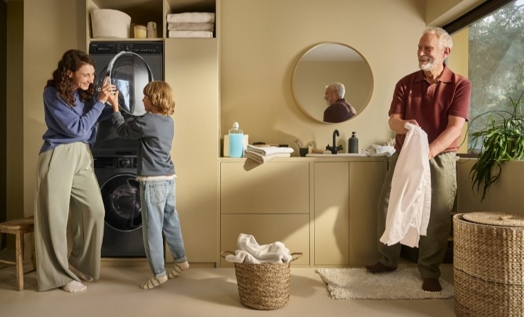 mama z synem stoją przy pralce i suszarce, dziadek przygląda się z boku