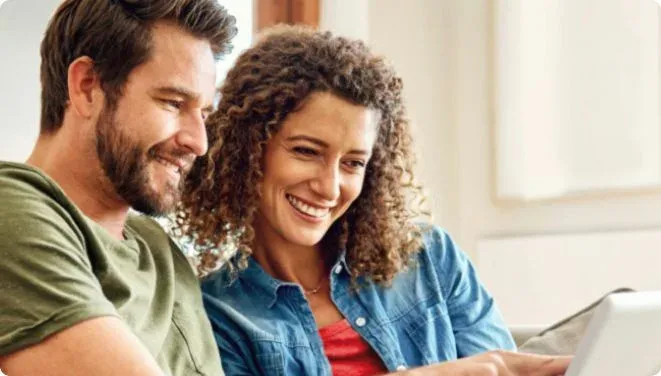 Mężczyzna i kobieta patrzą na ekran laptopa.